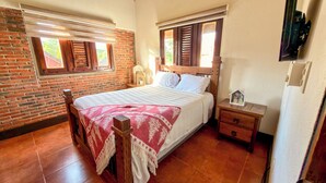 Una camera da letto con una parete in mattoni, un letto di legno, un comodino e una piccola casa decorativa sul comodino.