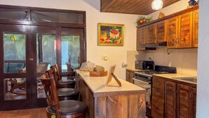 Una cucina con mobili in legno, un fornello e un'area pranzo con sedie.