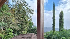 Una struttura in legno con tetto in tegole, immersa nel verde e circondata da alberi alti.