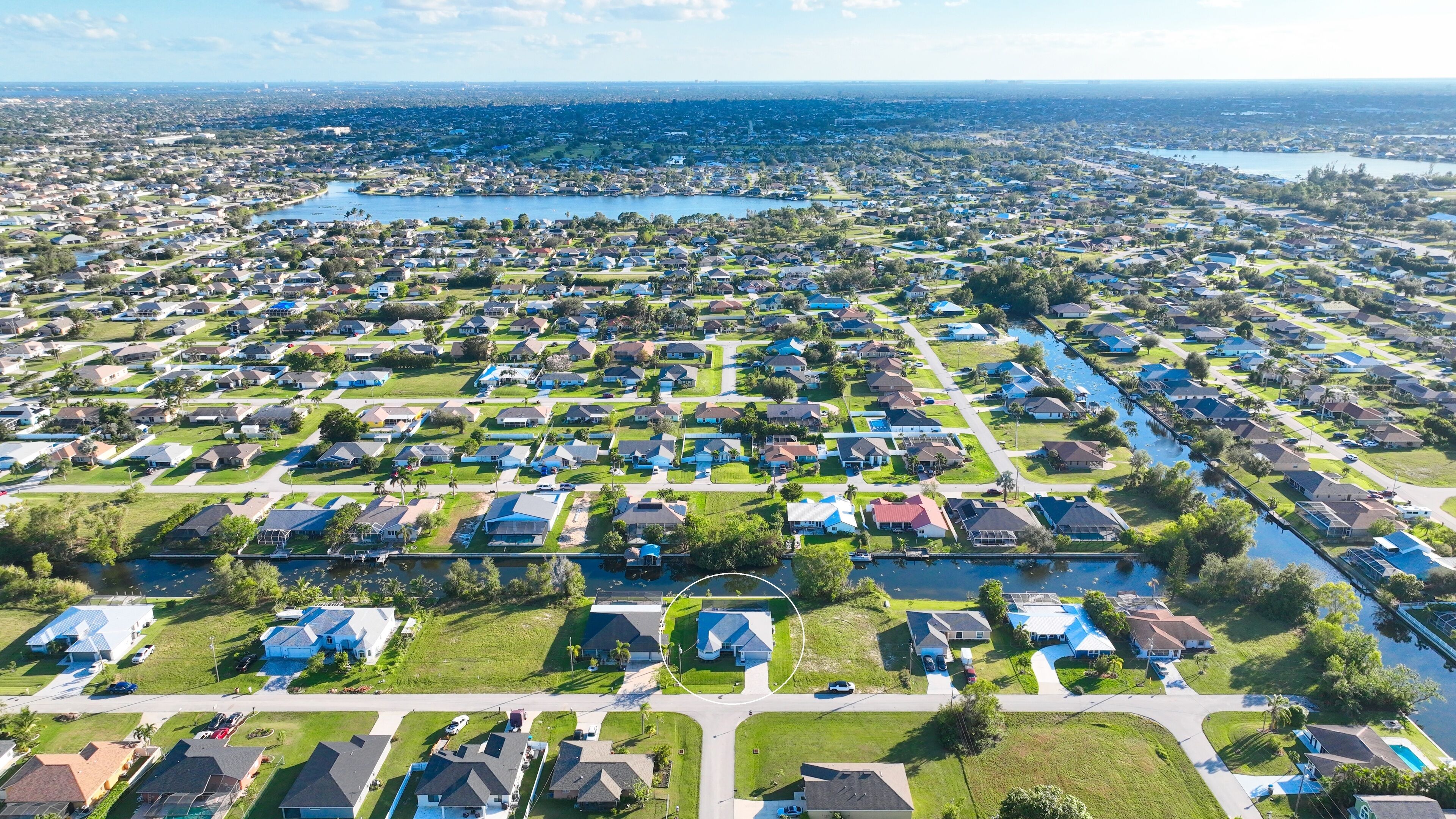 An aerial view of a residential area with houses, roads, and a body of water.