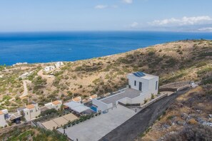 Ein Küstenwohngebiet mit modernen Häusern, einer gepflasterten Straße und Blick auf das Meer.
