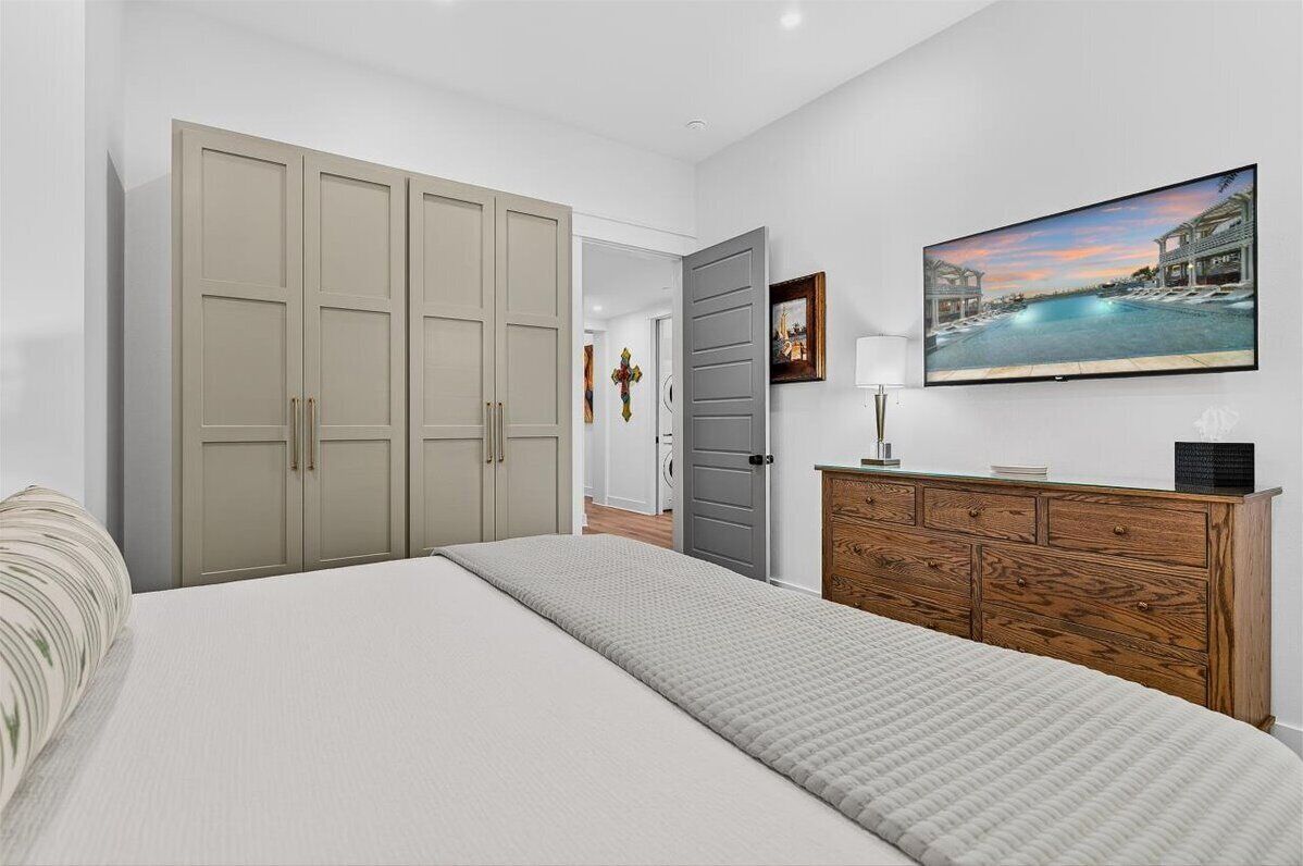 A bedroom with a large bed, a wardrobe, a dresser, and a painting on the wall.