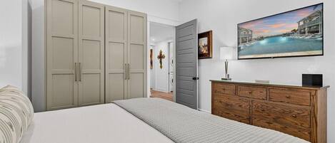 A bedroom with a large bed, a wardrobe, a dresser, and a painting on the wall.