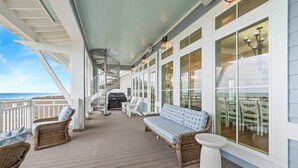 A covered outdoor area with wicker furniture, a white bench, and a small white table. - Casa de Playa 112 DAR (Port Aransas)
