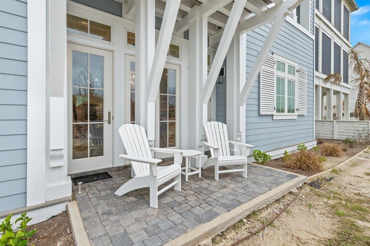 Ein Haus mit einer Veranda und zwei Adirondack-Stühlen sowie einem kleinen Tisch.