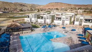 Una grande piscina circondata da edifici moderni, con vista su delle colline sullo sfondo.