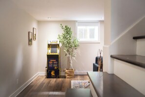 A hallway with a wooden floor, a potted plant, and a Pac-Man arcade machine.
