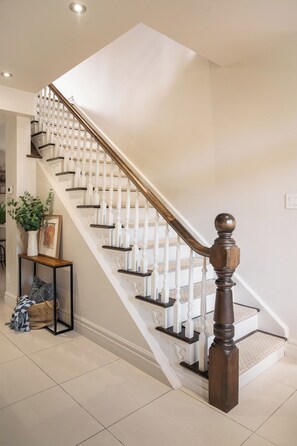 A staircase with white balusters and dark wooden handrails, leading to an upper floor.
