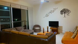 Ein modernes Wohnzimmer mit einer Couch, einem Couchtisch, einem Fernseher und dekorativer Wandgestaltung.