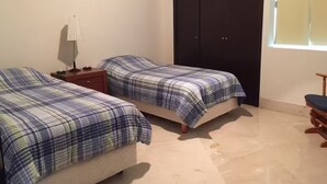 Ein Schlafzimmer mit zwei Betten, einem Nachttisch, einem Kleiderschrank und einem Fenster.