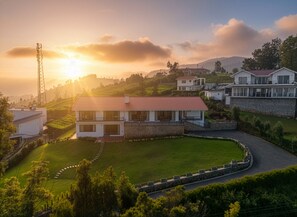 A modern house with a red roof, surrounded by a well-maintained lawn and a curved driveway. - amã Stays & Trails The Long House, Coonoor (Coonoor)