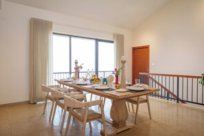 A dining area with a long table, chairs, and a staircase with a railing. - amã Stays & Trails The Long House, Coonoor (Coonoor)