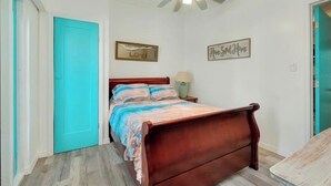 A bedroom with a wooden bed, a ceiling fan, and two wall decorations.