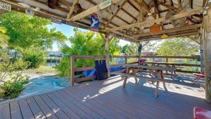 A wooden deck with picnic tables and a covered area with a metal roof.