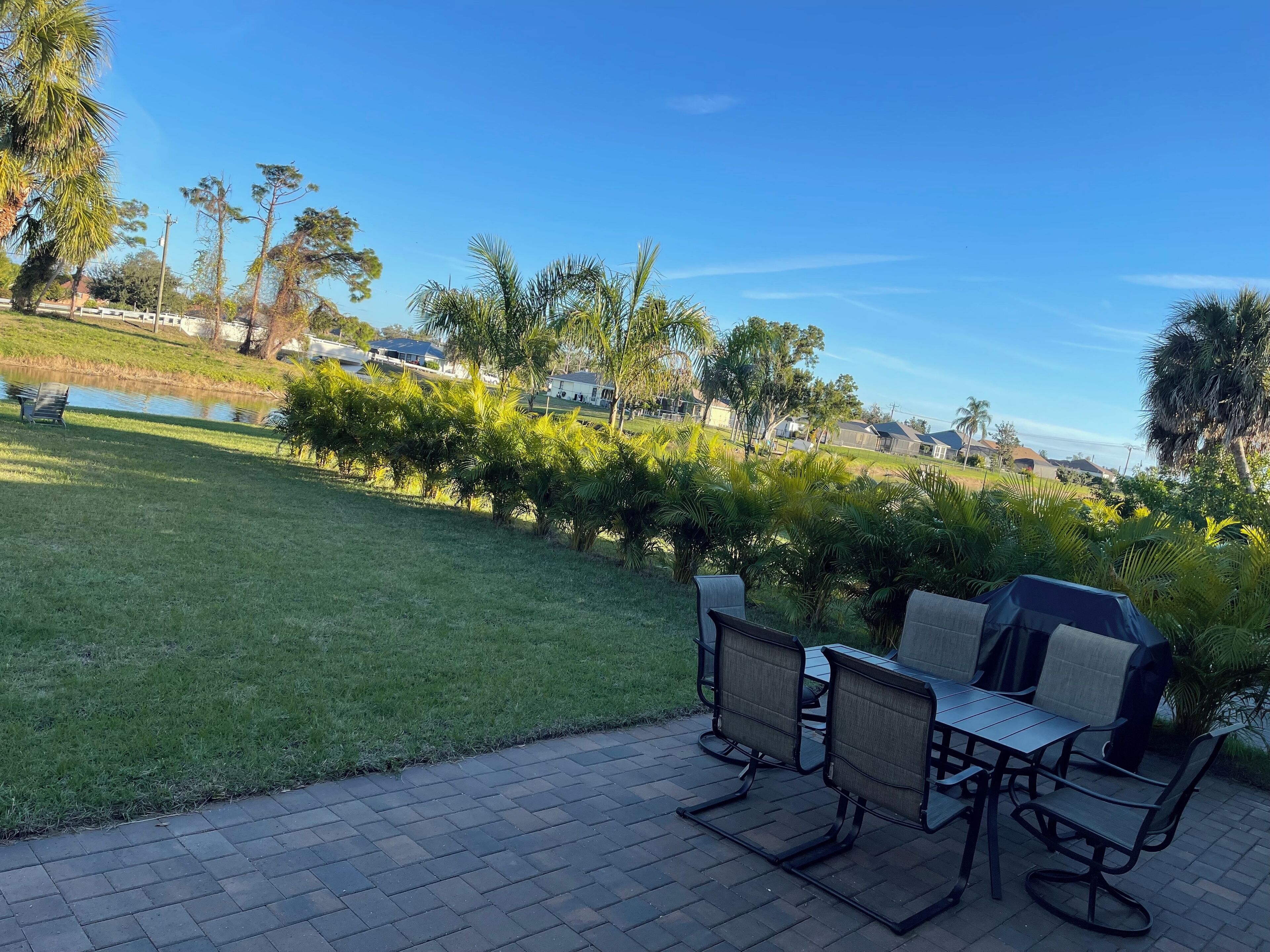Ulkoterassi, jossa on pöytä ja tuoleja, pieni lammikko ja näkymä taustalla oleviin taloihin.