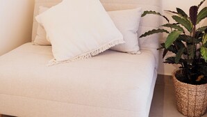 A beige sofa with two pillows, a woven plant pot, and a plain wall. - OAZA Romance Suite with Jacuzzi | Catania (Catania)