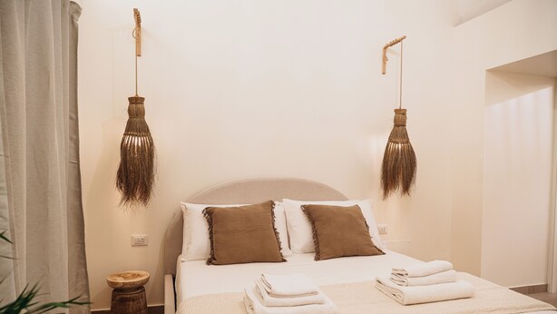 A neatly made bed with two pillows, a bedside table, and a hanging light fixture. - OAZA Romance Suite with Jacuzzi | Catania (Catania)