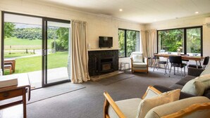 Un salón amplio con chimenea, televisor y comedor con vistas al exterior.