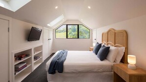Un dormitorio con cama, televisor en la pared, ventana y estantería.