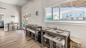 A dining area with a long table, benches, and a window with blinds.
