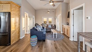 A spacious living area with a ceiling fan, a kitchen with a refrigerator, and a dining area with a table.