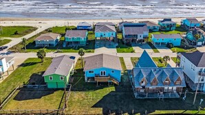 A coastal residential area with houses featuring gabled roofs and a beach in the background.