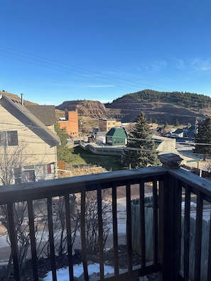 A residential area with houses, a green-roofed building, and a hilly landscape in the background.
