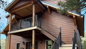 A two-story log cabin with a balcony and a staircase leading to the upper level. - Bear House in the mountains Cuchara Co. (La Veta)