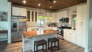 A spacious kitchen with wooden flooring, white cabinets, a central island, and pendant lighting. - Bear House in the mountains Cuchara Co. (La Veta)