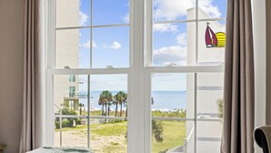 Une chambre d’hôtel dotée d’une grande fenêtre donnant sur la plage et l’océan.