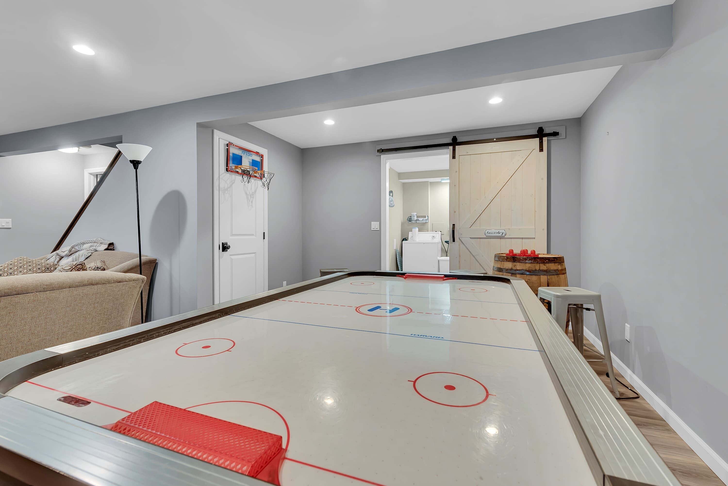 Een kamer met een jeu de boules tafel, een bank, een lamp en een deur naar een andere ruimte.