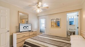 Un dormitorio con cama, cómoda, tocador con espejo, ventilador de techo y un cartel que anuncia alquileres vacacionales.