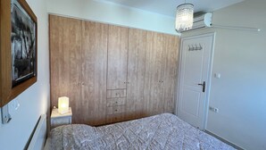 Una camera da letto con un'ampia armadiatura in legno, un letto con biancheria a fantasia, un lampadario e una porta dotata di attaccapanni.