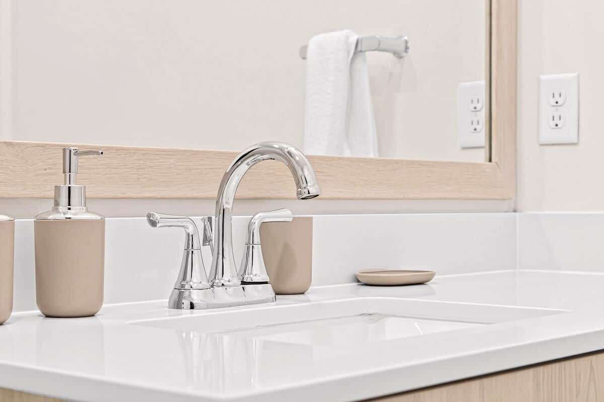 Polished vanity with chrome faucet, minimalist décor, and neatly arranged essentials for a spotless, modern touch.