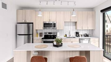 Bright, Fully Equipped Kitchen - Sleek kitchen with stainless steel appliances, bar seating, and all essentials for cooking or enjoying a morning coffee.