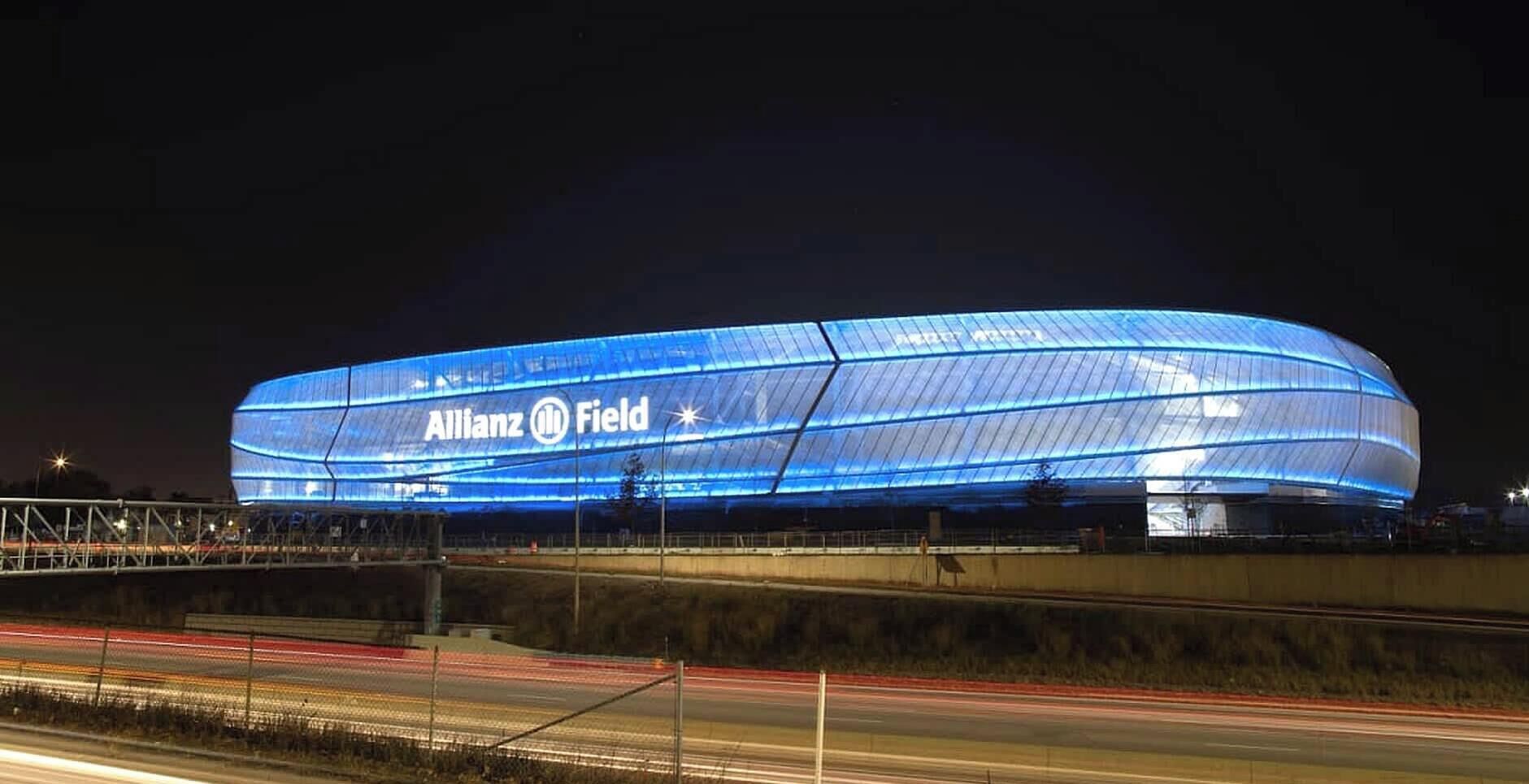 A large, modern stadium with the name "Allianz Field" illuminated on its facade.