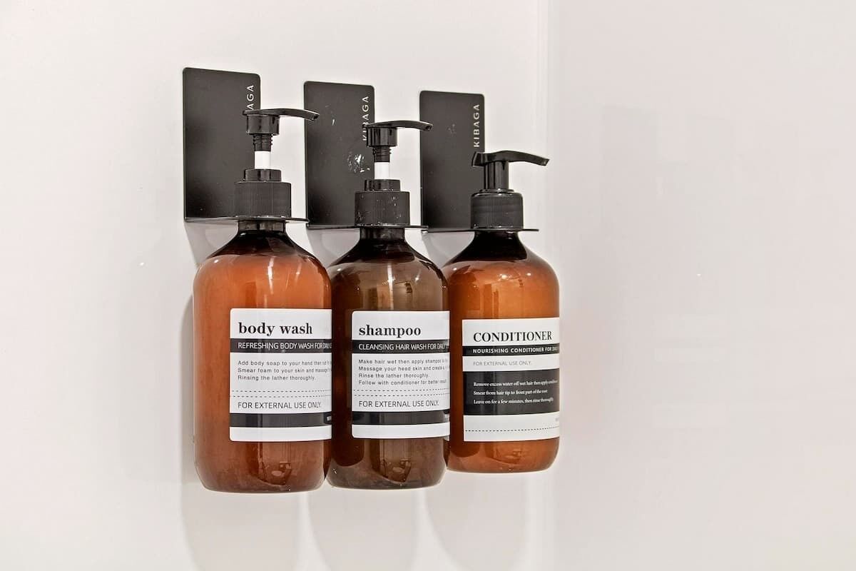 Three bottles of body wash, shampoo, and conditioner on a wall-mounted dispenser.