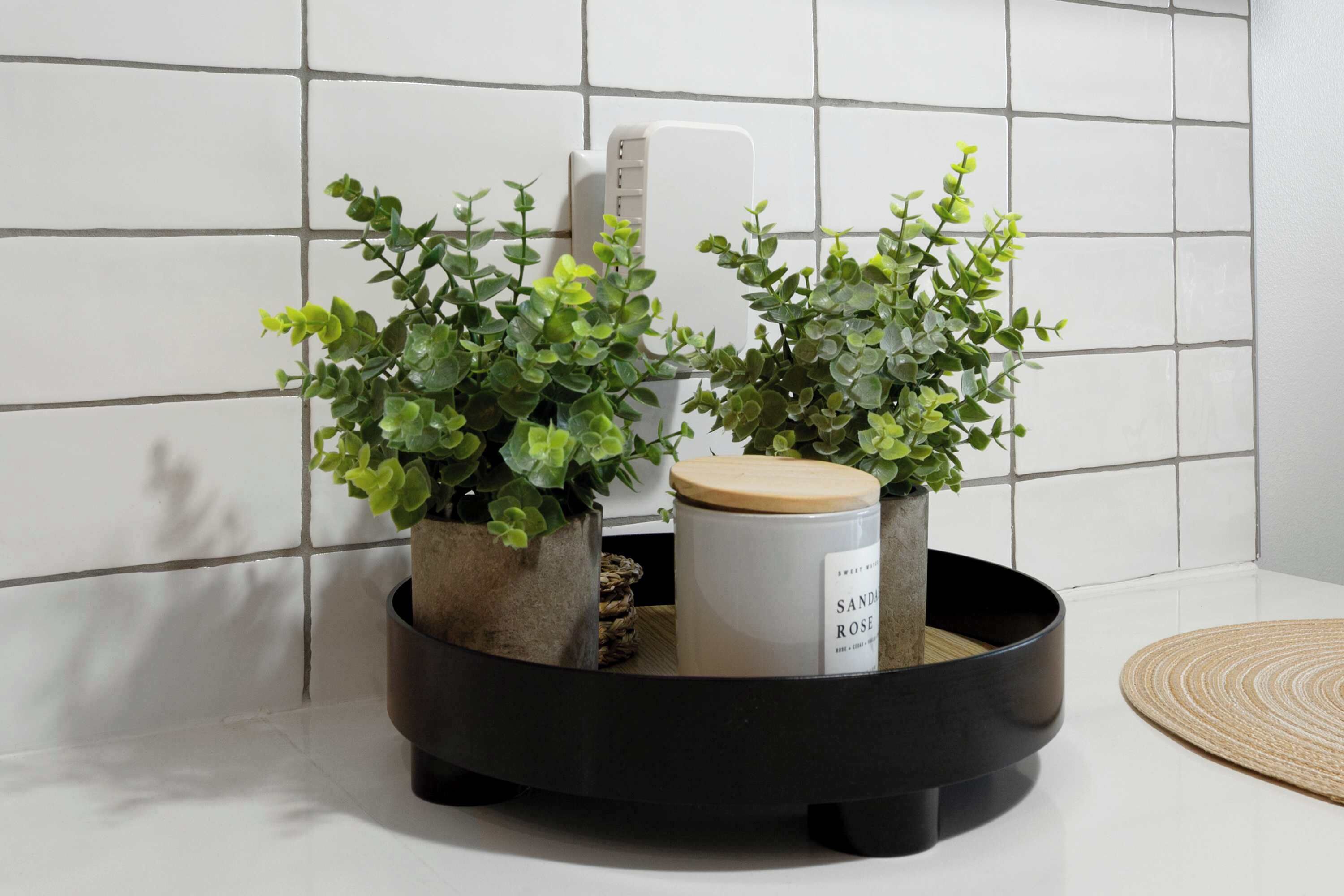 En køkkenbordplade med to krukkeplanter og en hvid beholder med etiket.