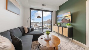 Un salon moderne avec un canapé, une table basse ronde et un téléviseur posé sur un meuble.