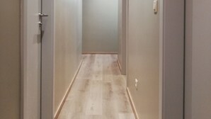 A narrow, well-lit hallway with wooden flooring and grey walls, leading to a room with a door at the end. - Au Vieux Gouvy: Family gîte, large enclosed garden & pets welcome (Gouvy)