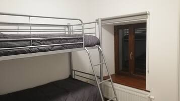 Een slaapkamer met een stapelbed, een raam en een radiator.