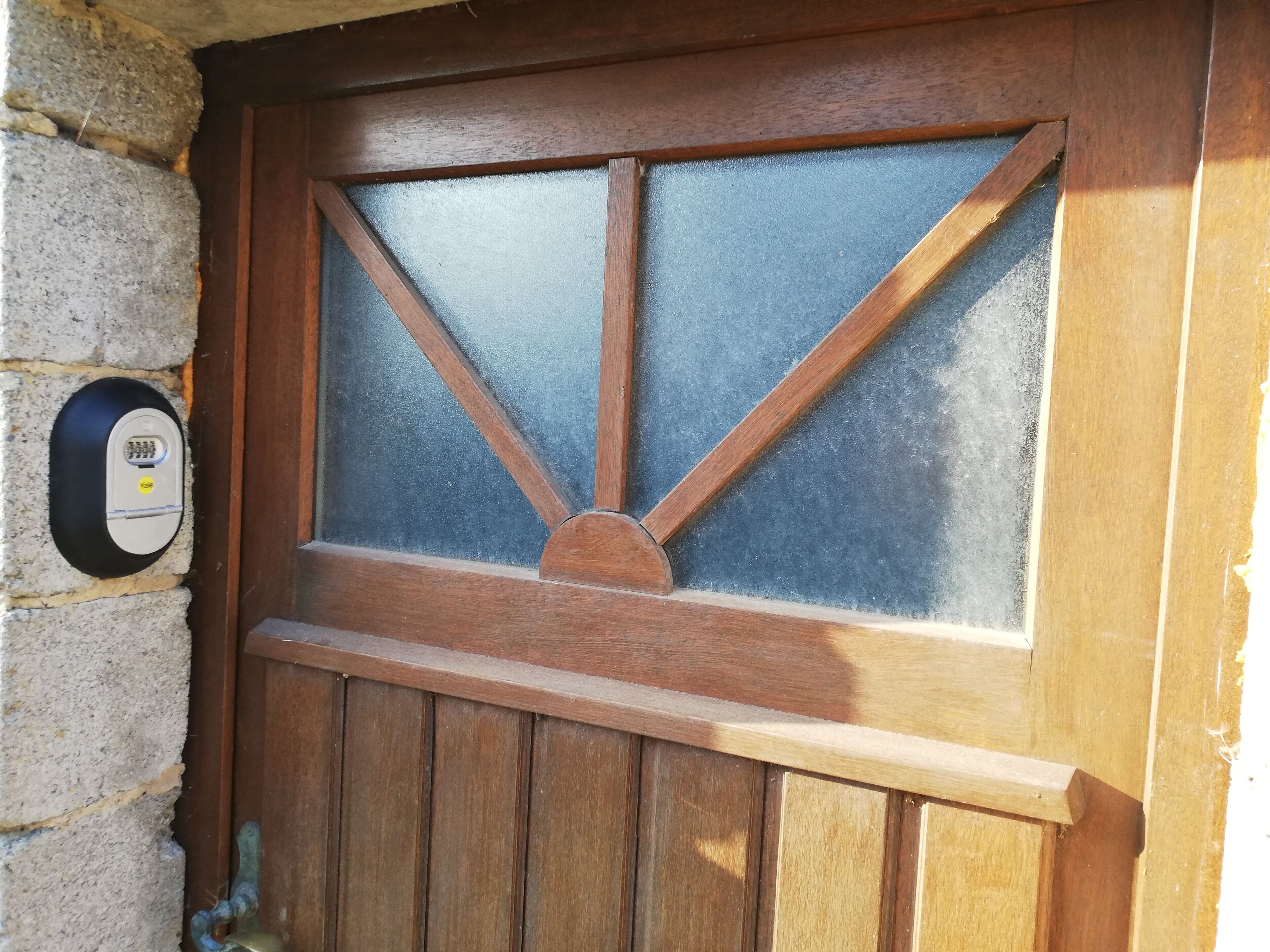 Une porte en bois avec un panneau de verre et un système de verrouillage à clavier.
