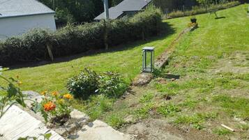 A residential area with a pathway leading to a house, surrounded by greenery and a small garden with flowers.