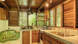 Una cocina rústica con armarios de madera, un lavamanos grande y una ventana con persianas.