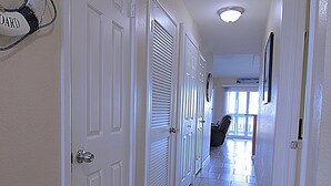 A hallway with white doors, a tiled floor, and a ceiling light.