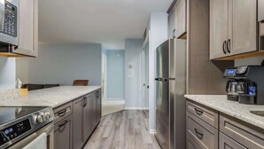 A modern kitchen with stainless steel appliances, wooden cabinets, and a marble countertop. - Club Ocean Villas I 42 (Ocean City)