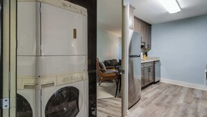 A laundry room with stacked washers and dryers, a dining area with a chair, and a kitchen with a refrigerator and cabinets. - Club Ocean Villas I 42 (Ocean City)