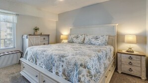 Ein Schlafzimmer mit Bett, Nachttischen, einem Schminktisch und einem Deckenventilator.