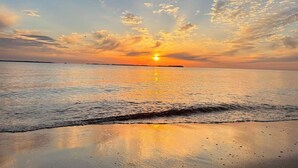Una playa al atardecer con olas tranquilas y cielo despejado.