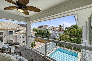 Ein Balkon mit Pool, Korbmöbeln und Deckenventilator.
